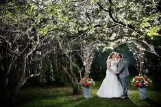 a bride and groom standing in front of trees