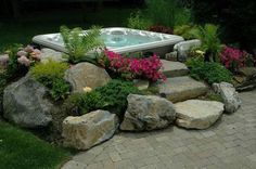 a hot tub surrounded by rocks and flowers