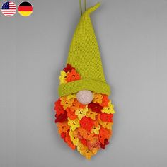 a crocheted gnome hat hanging from a hook on a gray wall with an american flag in the background