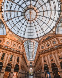 the inside of an indoor shopping mall with glass ceiling and high arched windows on both sides