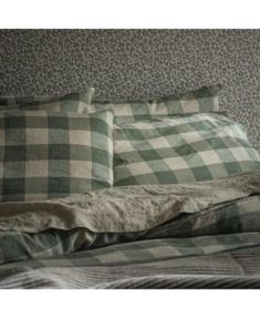 an unmade bed with green and white checkered sheets