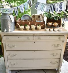 an old dresser is decorated with potted plants and bunting flags in the background