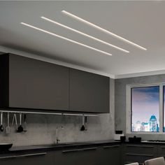 a kitchen with grey cabinets and black counter tops next to a large window that looks out onto the city