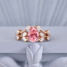 a pink diamond ring sitting on top of a white cloth