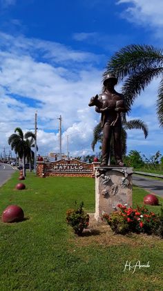 a statue of a man holding a baseball bat on top of a lush green field