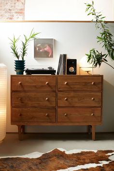 a wooden dresser sitting next to a potted plant