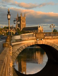 a bridge that is over some water with a clock tower in the backgroud