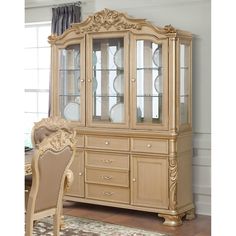 an antique china cabinet with glass doors and gold trimmings, in a dining room