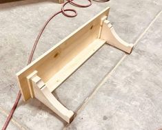 a piece of wood sitting on top of a floor next to a power cord and wires