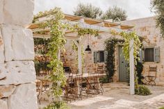 an outdoor dining area with tables and chairs under the pergolated roof, surrounded by greenery