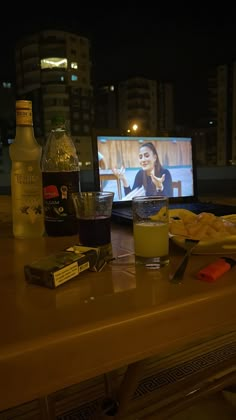 a table with food and drinks on it in front of a tv