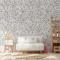 a white couch sitting in front of a wall covered in black and white polka dots