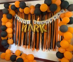 an orange and black party decoration with balloons