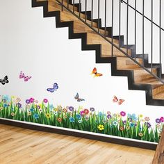 a stair case with flowers and butterflies painted on the wall next to a wooden floor