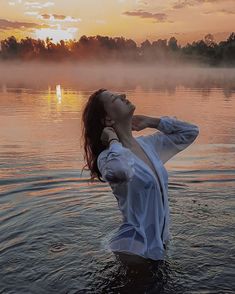 a woman standing in the water at sunset