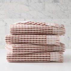 three brown and white striped towels stacked on top of each other in front of a marble wall