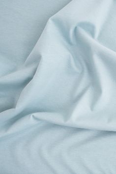 an unmade bed with light blue sheets and white pillow cases on top of it