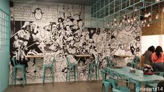 people are sitting at tables in front of a wall with cartoon drawings on the walls