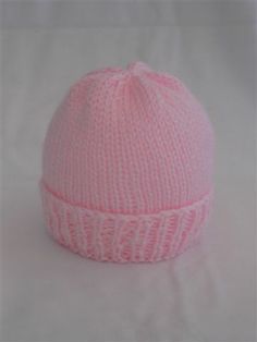 a pink knitted hat sitting on top of a white sheet