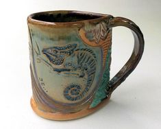 a ceramic mug with an image of a lizard on the front and side, sitting on a white surface