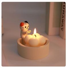 a candle that is sitting in a bowl with some kind of cat on top of it