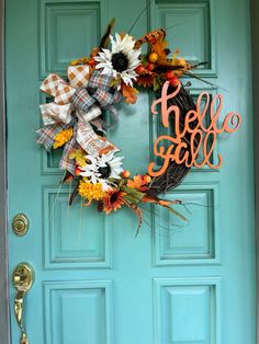 a wreath with the word hello fall is hanging on a blue front door that says hello fall