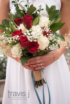 a bride holding a bouquet of red and white roses