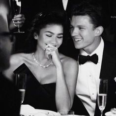 a young man and woman sitting next to each other at a dinner table