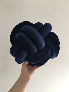 a hand holding up a blue knot cushion