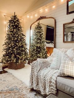 a living room with a christmas tree in the corner and a mirror on the wall