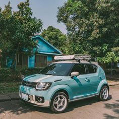 a small blue car parked in front of a house