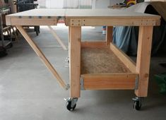 a workbench made out of plywood and wood with wheels on the floor