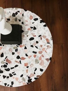 a white vase sitting on top of a table next to a black book and cup