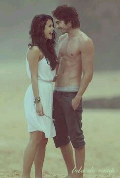 a man and woman standing next to each other on the beach