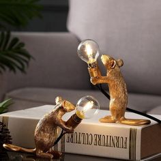 a lamp that is sitting on top of a book with a mouse holding a light bulb