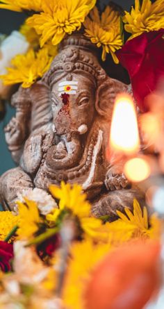 an elephant statue surrounded by yellow flowers and candles with the words yogazenial written on it