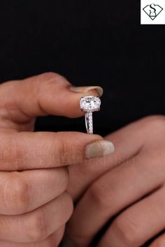 a woman's hand holding an engagement ring with a diamond on the middle finger