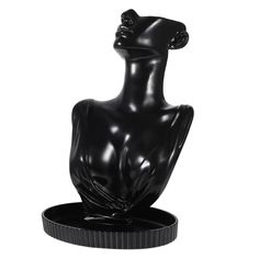 a black sculpture sitting on top of a round base in the shape of a woman's head