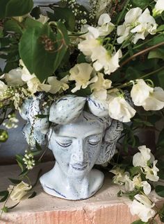 a vase with white flowers in it sitting on top of a brick wall next to a planter