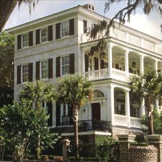 a large white house with palm trees in front