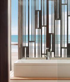 a bath tub sitting under a window next to the ocean