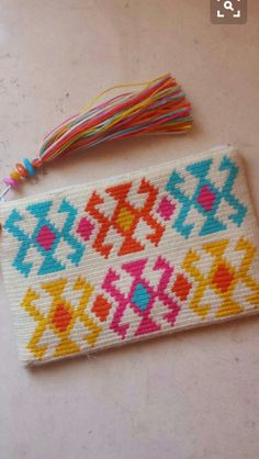 a small bag with a tassel on top of it sitting on a white table