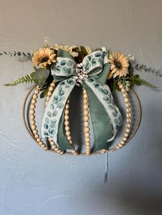 a wreath with sunflowers and pearls hanging on the wall in front of a gray wall