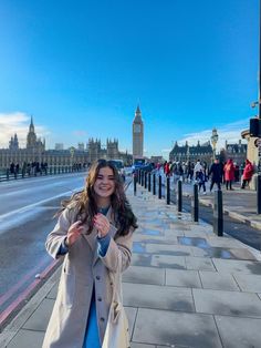 a woman standing on the sidewalk in front of big ben