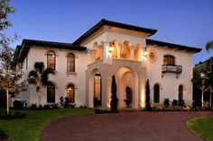 a large white house with lots of windows and lights on it's front entrance