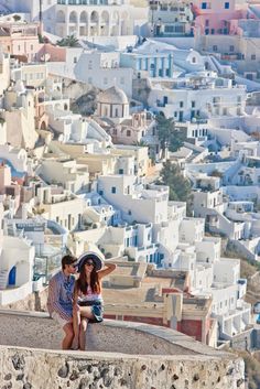 two people sitting on the edge of a building looking out over a cityscape