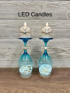 two blue glass candle holders with seashells in them and the words led candles