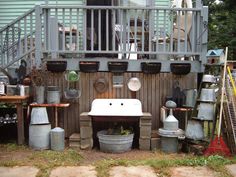 an outdoor kitchen with pots and pans on the wall, next to a deck