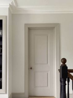 an empty room with white walls and wooden stairs, next to a bookcase full of books