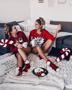 two women sitting on top of a bed with candy canes and marshmallows